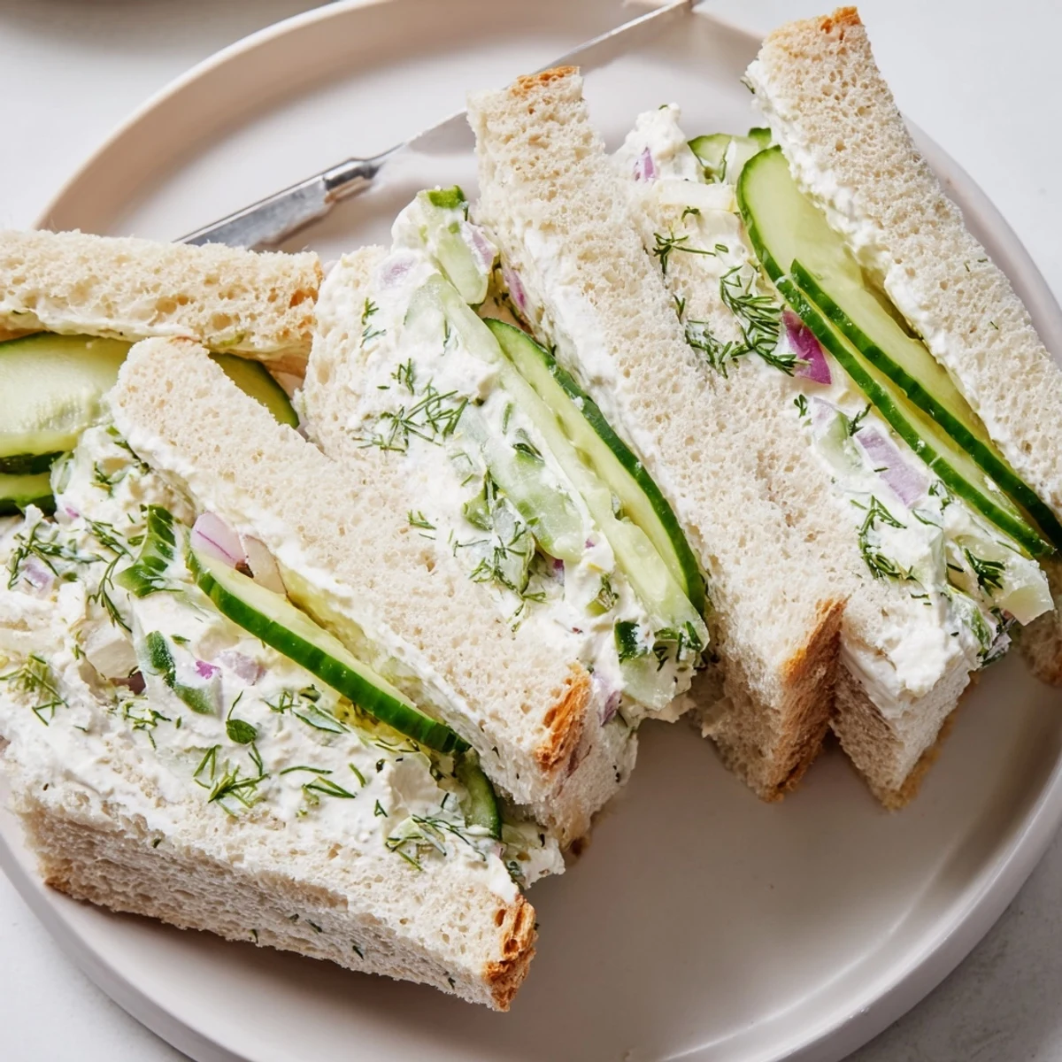 Creamy cucumber salad sandwiches on white bread with fresh dill and crisp red onion
