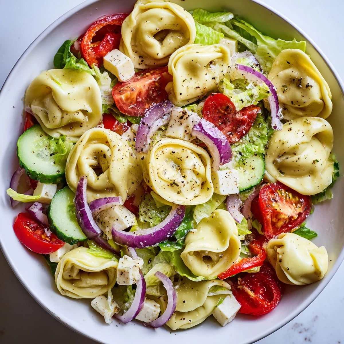 Hearty fresh grinder tortellini salad recipe featuring cheese tortellini, roasted red peppers, pepperoncini, and sliced red onions