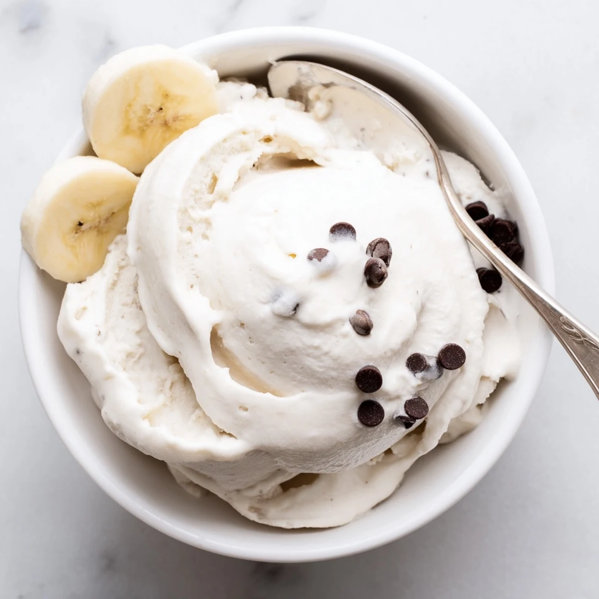 Smooth banana nice cream swirled with cocoa powder in a chilled glass serving dish