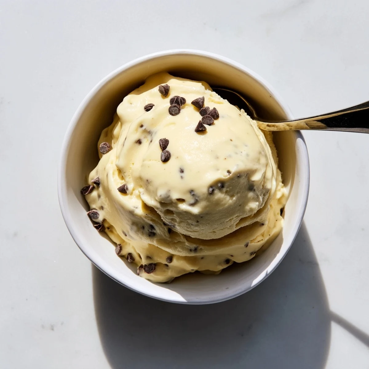 Vibrant bowl of dairy-free banana nice cream topped with crushed nuts and dark chocolate shavings