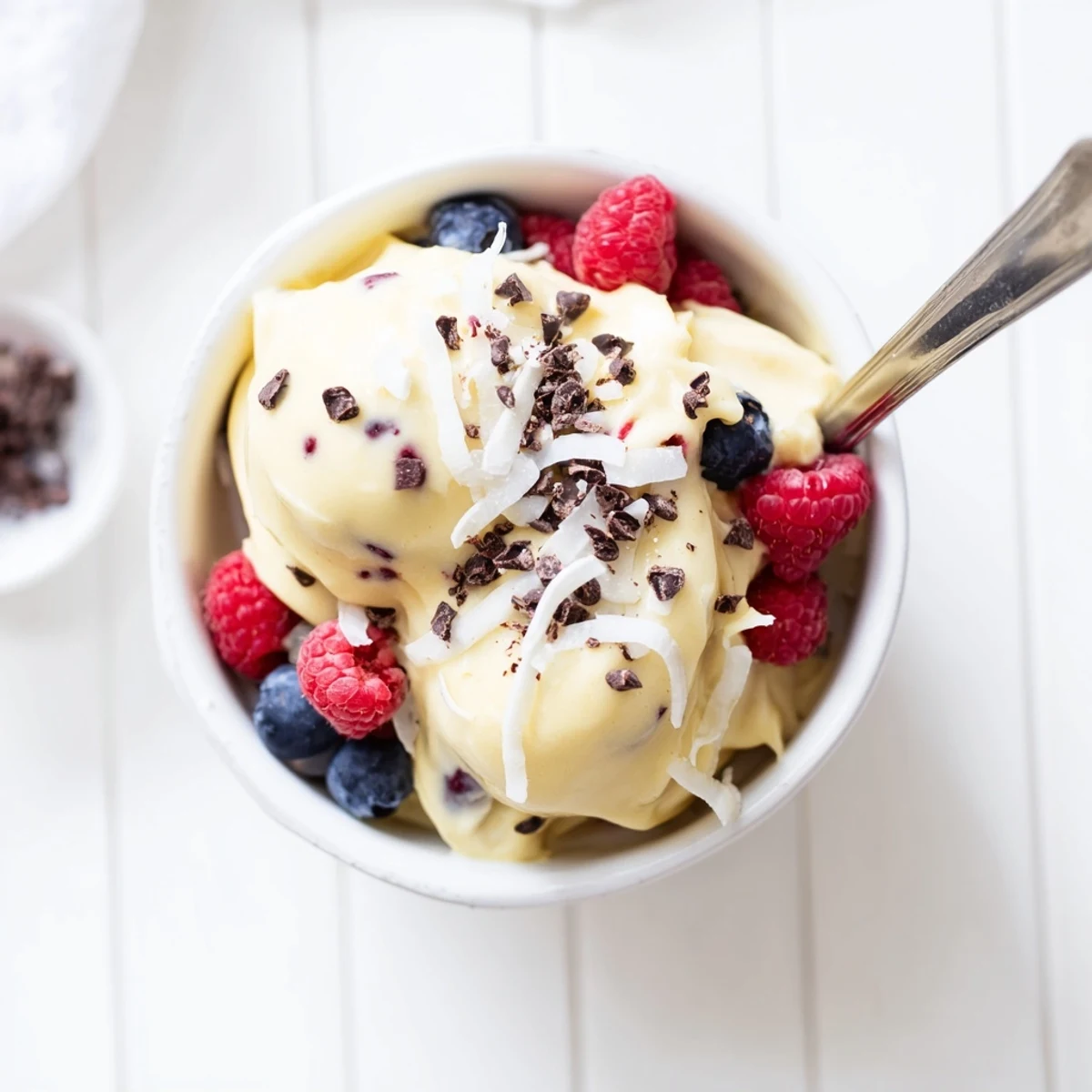 Whipped frozen banana nice cream with swirls of dark chocolate chips and a garnish of mint.