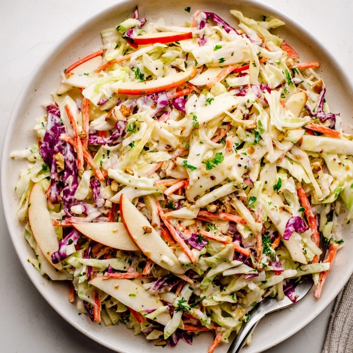 Bowl of Apple Coleslaw tossed with crunchy carrots, green onions, pecans.