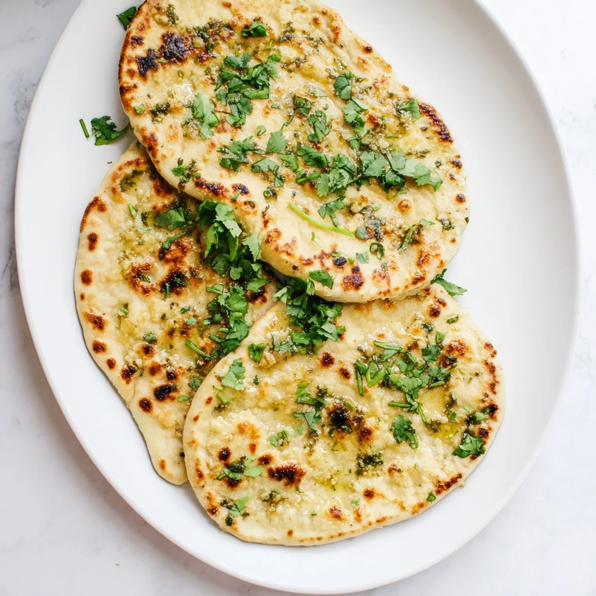 Pillowy Indian-inspired sourdough discard naan with golden char marks ready for curries