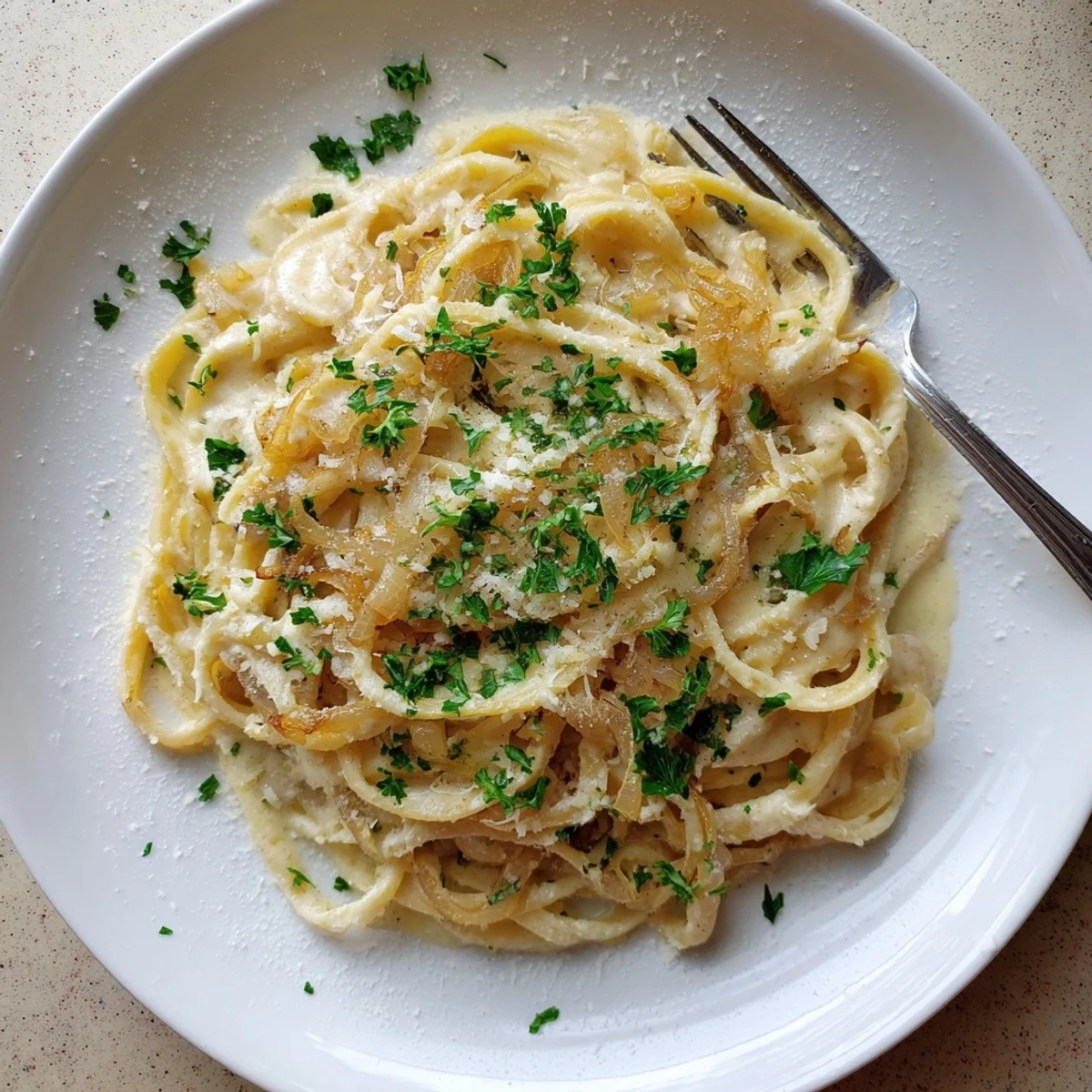 Plate of caramelized onion cream pasta featuring silky noodles coated in a rich Parmesan cream sauce