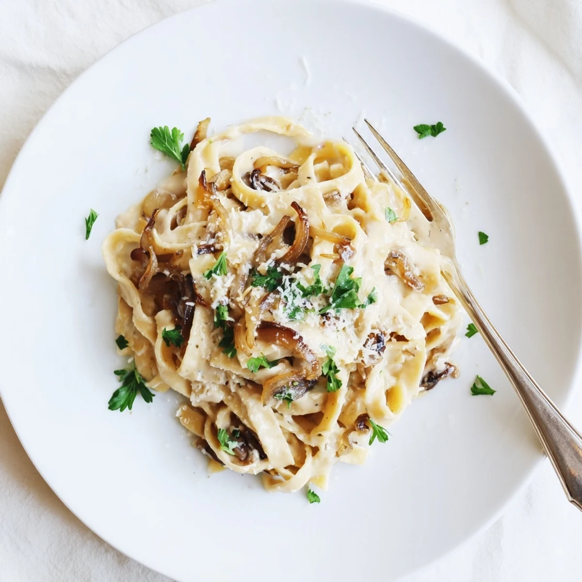 Golden brown caramelized onion cream pasta tossed in a velvety white sauce with fresh parsley garnish