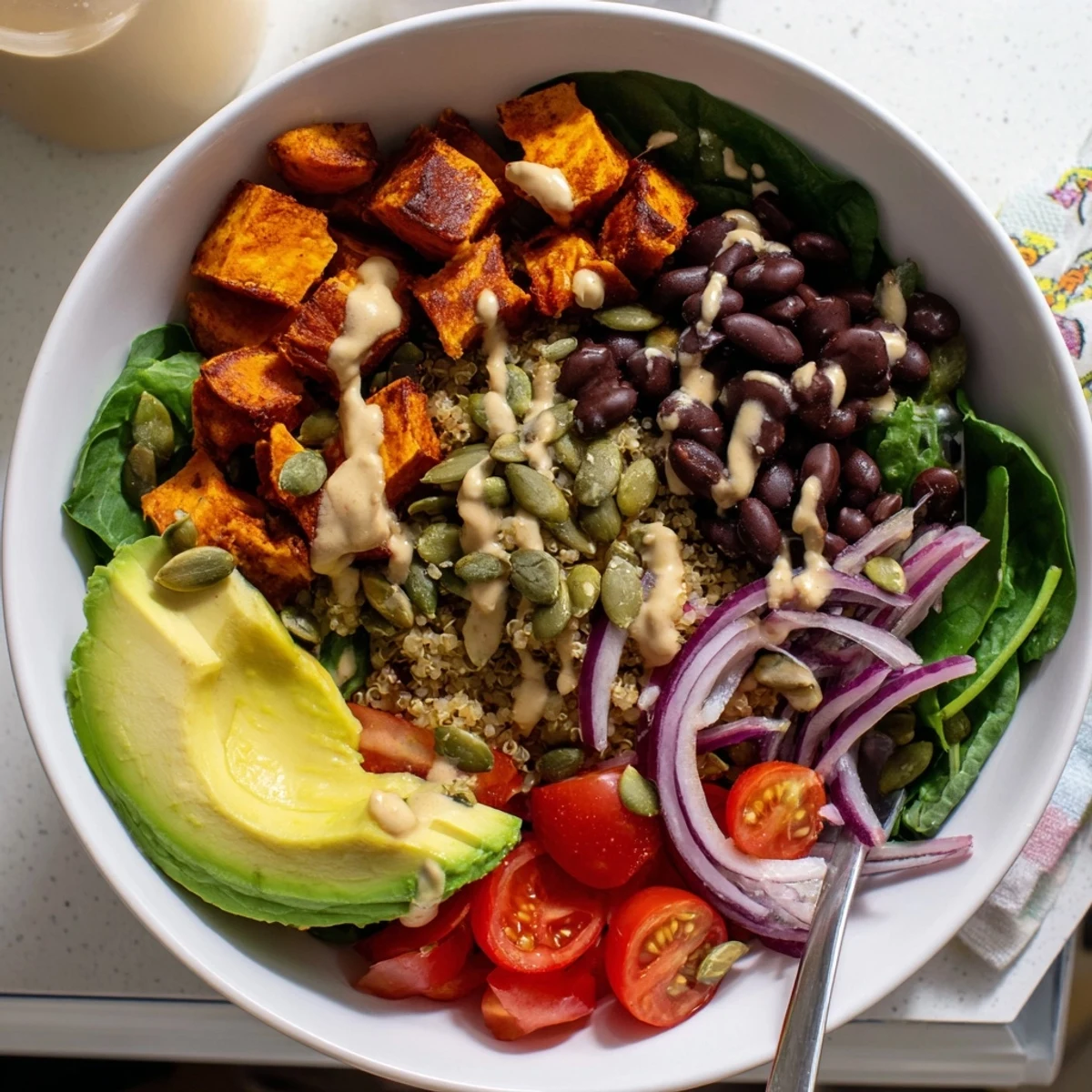 Roasted sweet potato bowl served over quinoa with black beans and fresh vegetables
