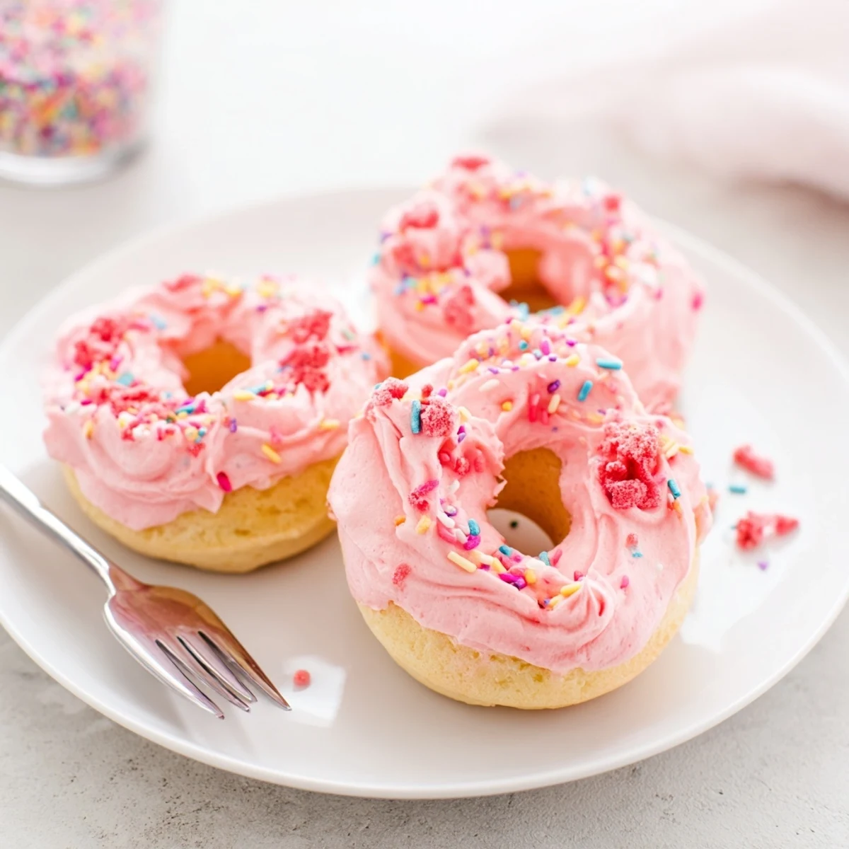 Golden baked strawberry buttercream frosted donuts piped high with creamy pink icing