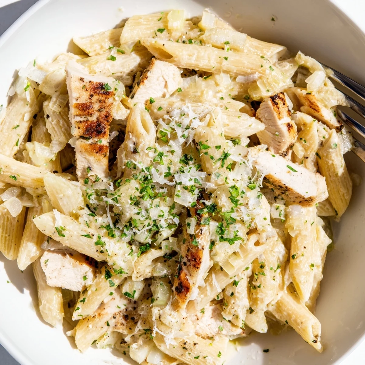 Creamy Garlic Parmesan Chicken Pasta topped with fresh parsley in a white bowl