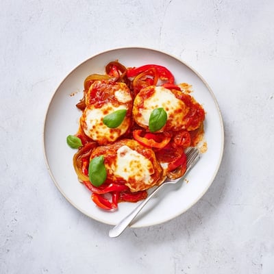Close-up of Italian Style Chicken with fresh basil garnish, served alongside crusty bread for dipping.
