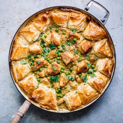 One Pan Chicken Korma Pie served in the skillet with a golden crust, alongside a simple green salad for a fresh contrast.