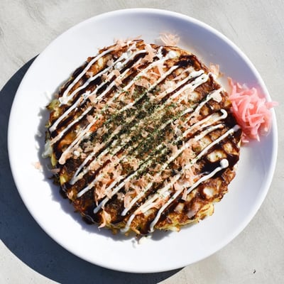 Close-up of a hearty Chicken Okonomiyaki served hot with cabbage, mayo swirls, and katsuobushi.