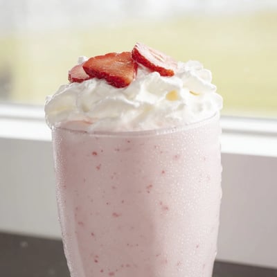 Creamy strawberry milkshake served in a chilled glass with a pink straw